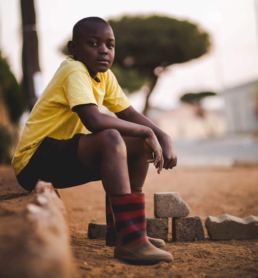 Menino negro sentando na calçada