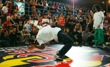 Homem dançando breaking e pessoas assistindo